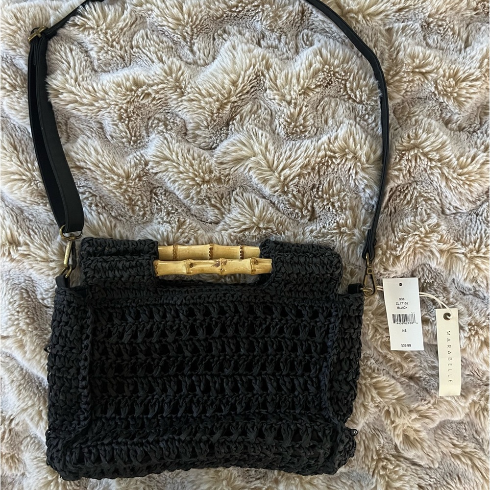 Black rattan woven handbag with bamboo handle and adjustable shoulder strap.